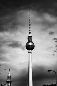 Low angle view of communications tower in city against sky