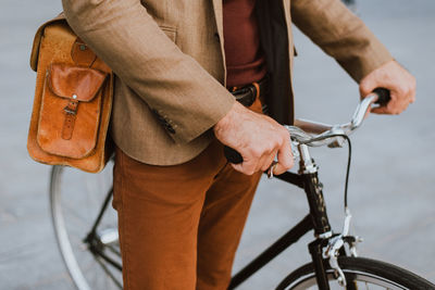 Midsection of man with bicycle standing on street