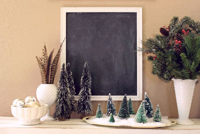 Close-up of christmas trees and blackboard at home