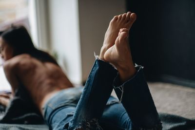 Rear view of shirtless man lying on floor at home