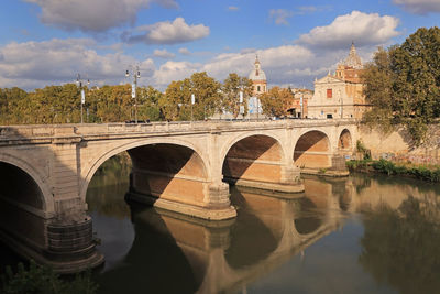 Arch bridge over river against sky