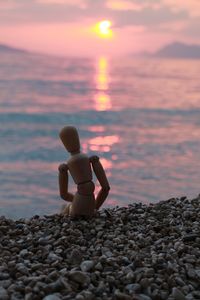 Close-up of figurine at beach during sunset