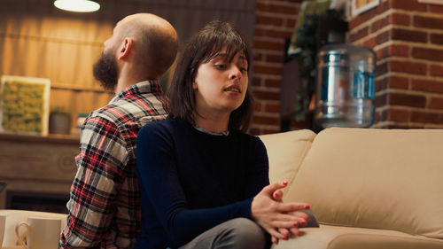 Side view of young woman sitting on sofa at home