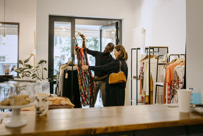 Male owner showing clothing to customer in store