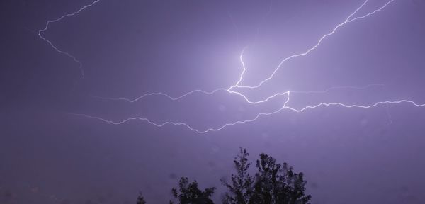 Low angle view of thunderstorm against purple sky