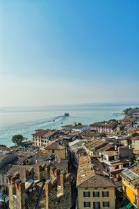 High angle view of buildings and lake garda against blue sky on sunny day