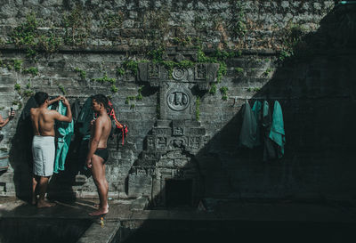 People standing by wall of old building