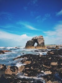 Rock formations by sea against blue sky