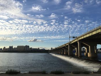 Bridge over river in city against sky