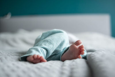 Low section of baby sleeping on bed