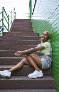 Side view of smiling young woman sitting on staircase