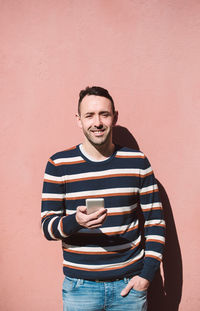 Portrait of young man standing against wall