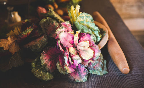 High angle view of leaf vegetables and rolling pin on table