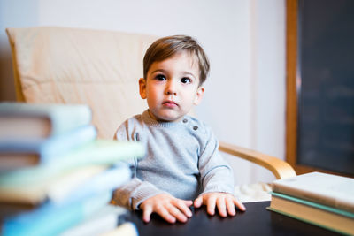 Cute boy with books on table at home