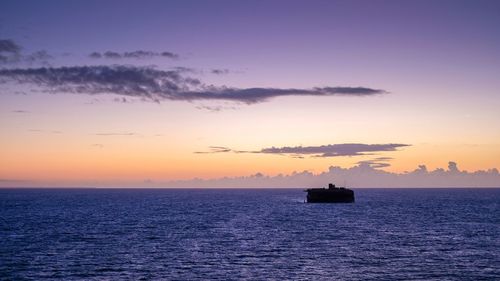 Silhouette boat in sea against clear sky during sunset