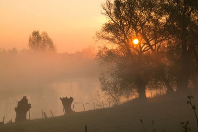 View of calm misty lake at sunset