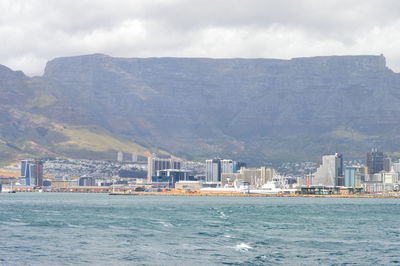 Sea by buildings in city against sky