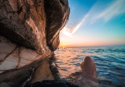 A man lies in the water under white rocks in abkhazia at sunset