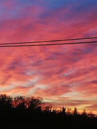 Low angle view of silhouette trees against orange sky