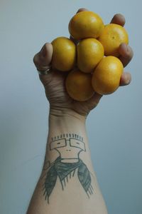 Close-up of hand holding fruits against wall