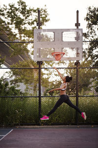 Sporty woman reaching basketball hoop