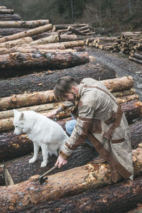 High angle view of young man with dog chopping wood in forest