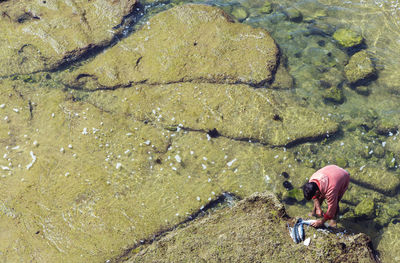 High angle view of man fishing at lakeshore on sunny day