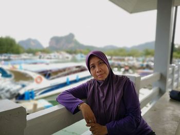 Portrait of young woman standing against built structure