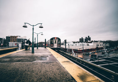 Train arriving at railroad station platform against sky