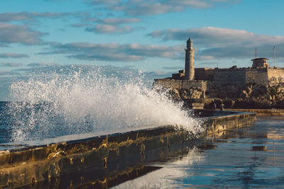 Sea waves splashing on shore against buildings