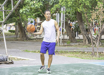 Full length of man playing basketball in court