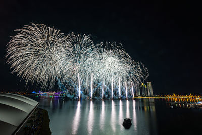 Reflection of firework display on river against sky