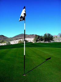 Scenic view of grassy field against blue sky