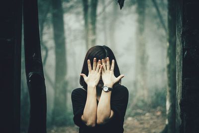 Portrait of person standing against curtain covering face