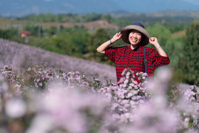 Woman walking in pink amaranth field in summer