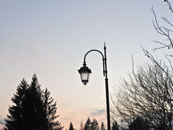 Low angle view of silhouette trees and street light against sky during sunset