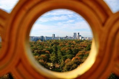 Trees and buildings from berlin city against sky through an architectural circle