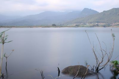 Scenic view of lake by mountains against sky