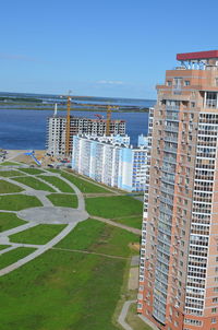 Scenic view of sea by buildings against clear blue sky