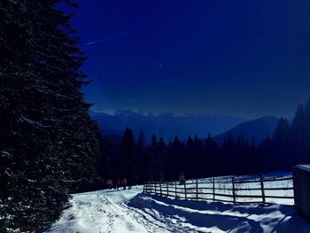 Snow covered land against sky at night
