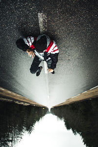 Upside down image of man lying on road in forest