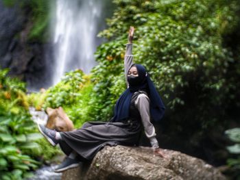 Rear view of man sitting on rock