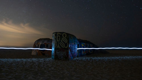 Built structure on beach against sky at night