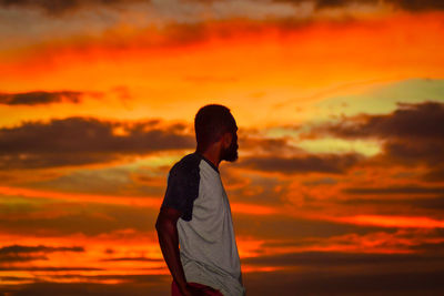 Side view of man standing against sky during sunset