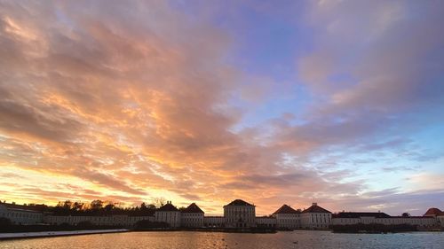 Buildings by sea against sky during sunset