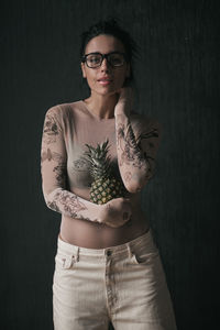 Portrait of young woman standing against black background