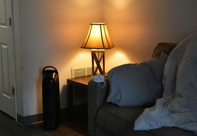 Electric lamp on bed against wall at home