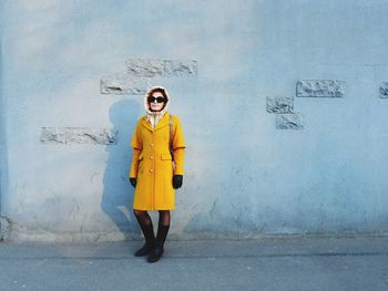 Portrait of woman standing against yellow wall