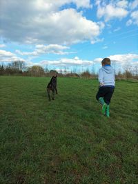 Rear view of woman walking on field against sky