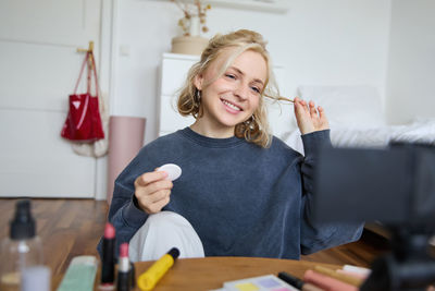 Portrait of young woman using mobile phone while sitting at home